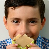 Comforted child smiling while holding and smelling a bar of homemade soap.